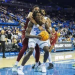 UCLA forward William Kyle III (24) is wrapped up and fouled by Rider forward Tyriek Weeks (31) at Pauley Pavilion on Monday. (Gina Ferazzi/Los Angeles Times)