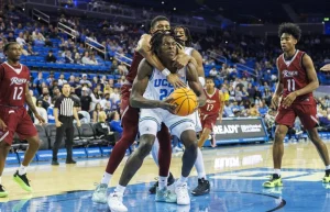 UCLA forward William Kyle III (24) is wrapped up and fouled by Rider forward Tyriek Weeks (31) at Pauley Pavilion on Monday. (Gina Ferazzi/Los Angeles Times)