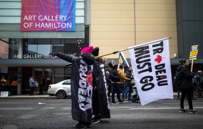 Protestors hold a flag reading 'Trudeau Must Go' outside the Hamilton Convention Centre, ahead of the Liberal Cabinet retreat, in Hamilton on Jan. 23, 2023. (Nick Iwanyshyn/The Canadian Press)